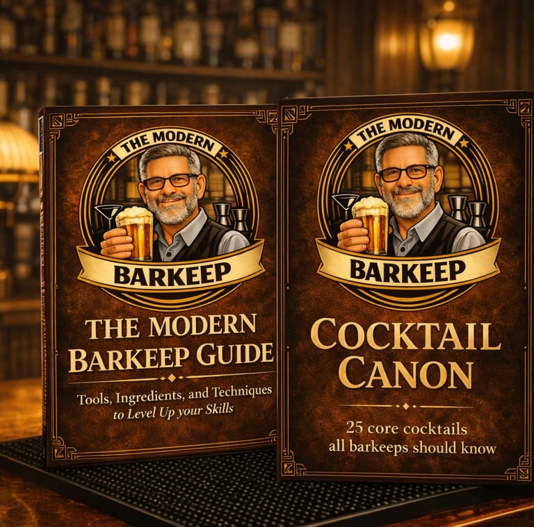 The Modern Barkeep Guide and Cocktail Canon books displayed on a bar top with vintage lighting.