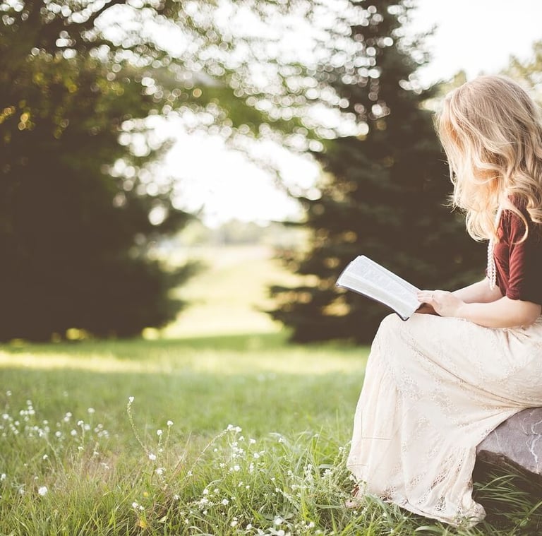 a woman sitting on a rock with a book