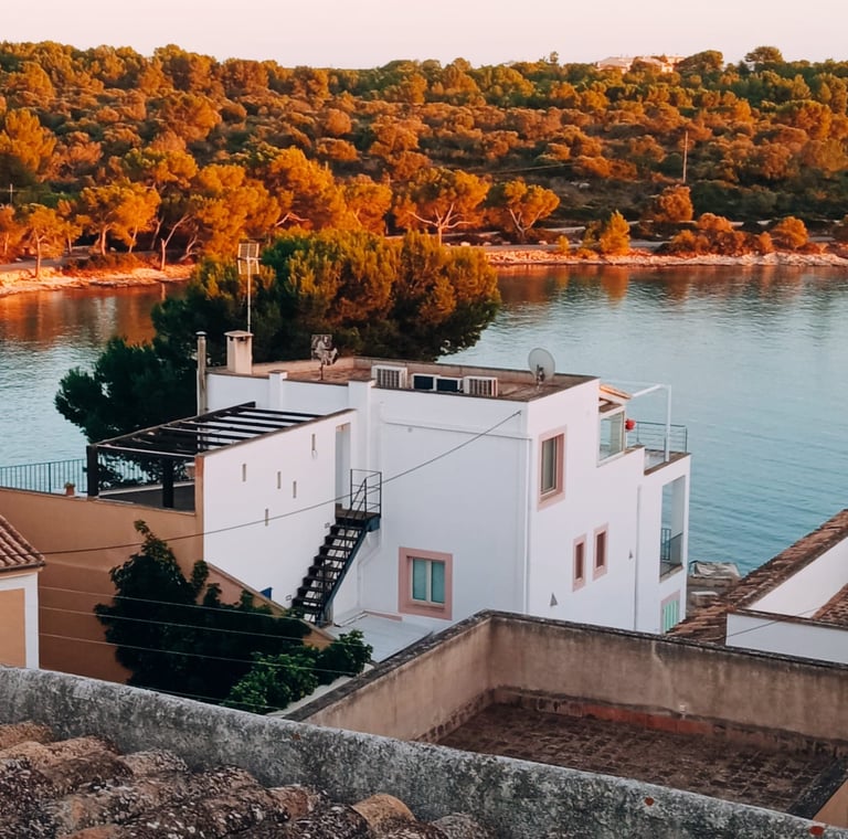 a white house with a staircase leading to a balcony in portocolom