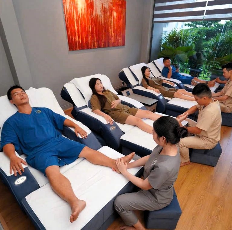 a group of people sitting in a row of beds in a spa and getting a massage