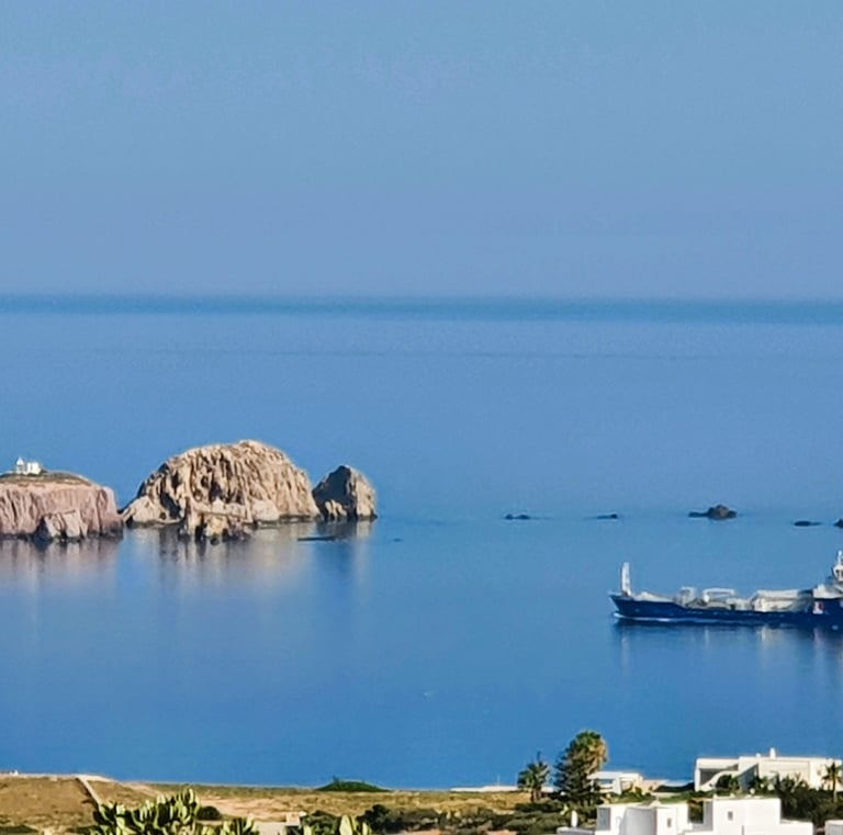 Sea scape of Paros looking to the sea, small rocky islands and a comertial vesel