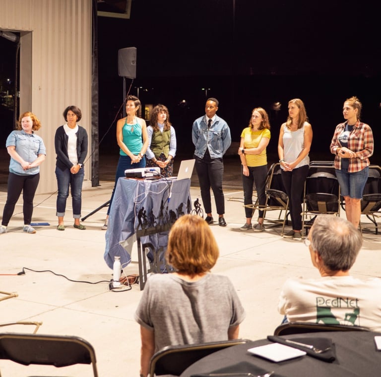 Staff members lined up in front of an audience, giving a presentation