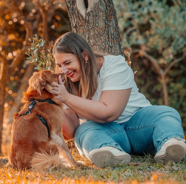 ragazza che sorride al proprio cucciolo seduta sotto un albero
