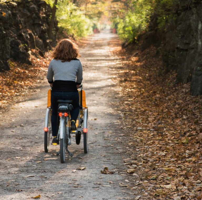 A person pedaling our "Giving Rides Bike" on a gravel trail