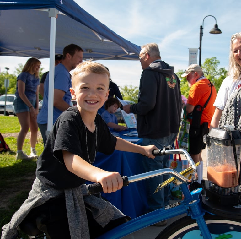 Child posing for the camera while powering our blender bike at an event!
