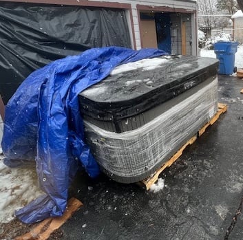 a hot tub in a driveway under a tarp