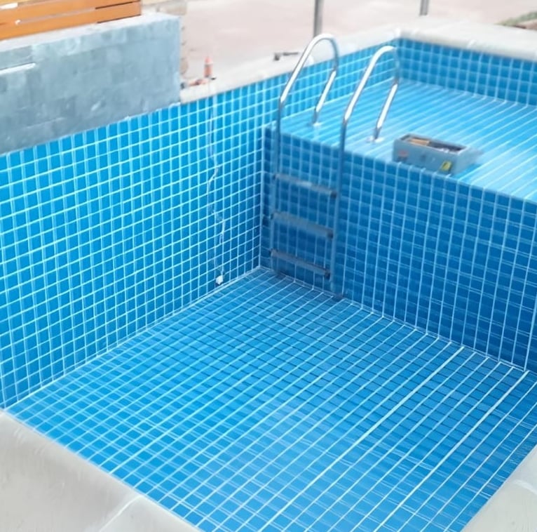 a pool with a blue tiled pool and a wooden deck