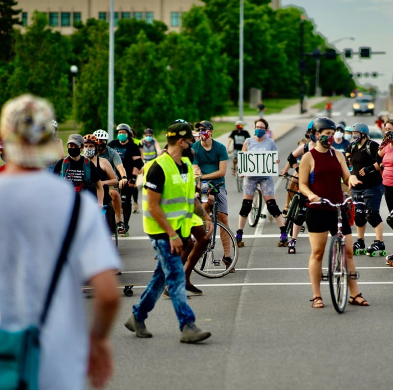 Bikers stopped on a road, with one holding a sign that reads "Justice"