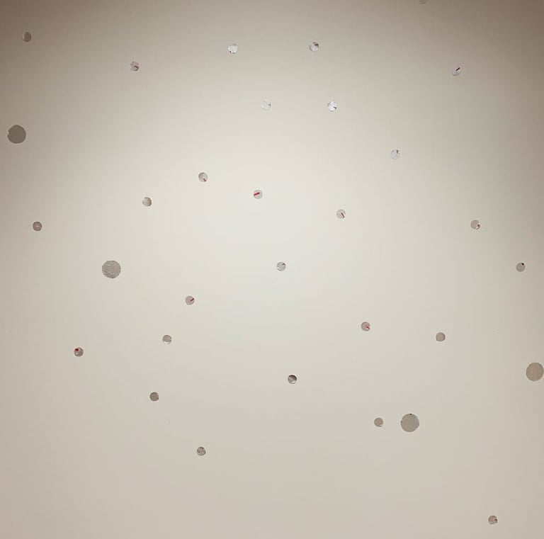 Small silver dot decals are scattered over a white wall, adding elegance with a playful touch.