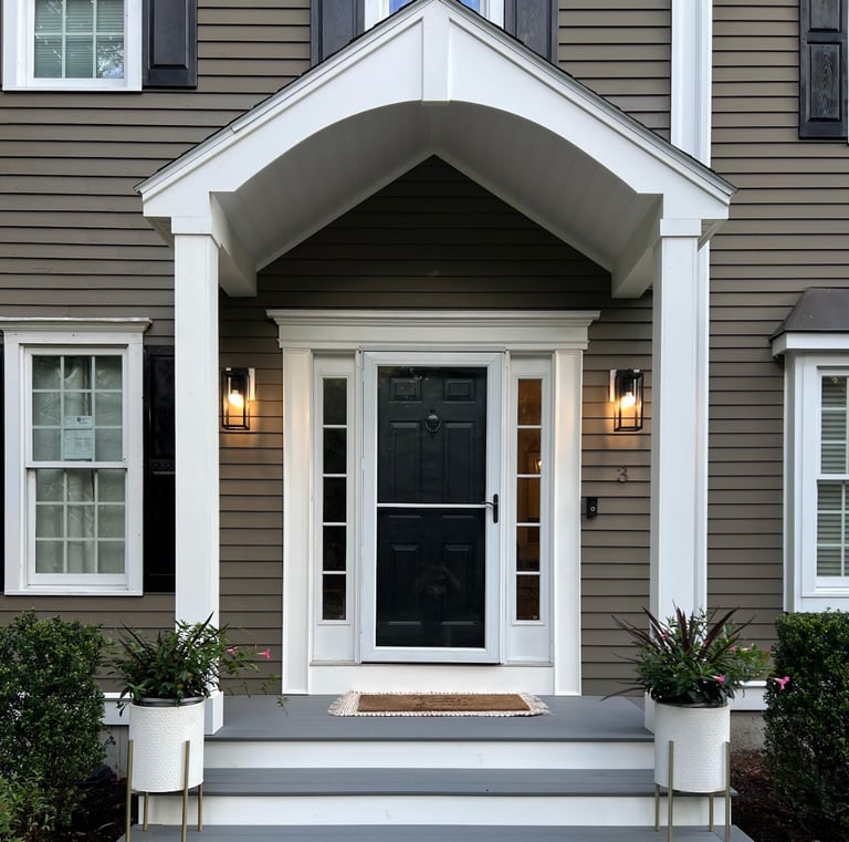a house with a black door and white steps leading up to a front door