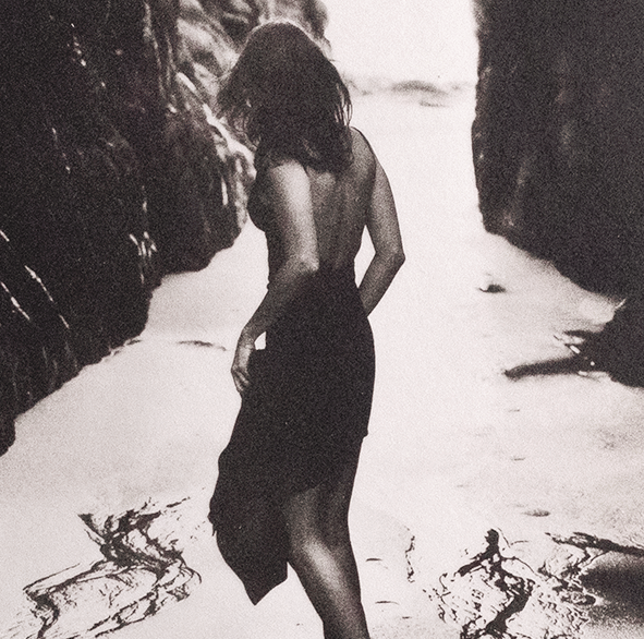 SIlver and Platinum photo of a woman in a black dress standing on a beach