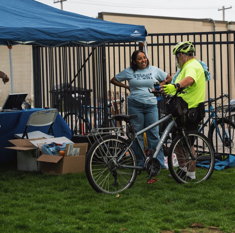 Man with his bike, speaking to a Local Motion staff member at their booth