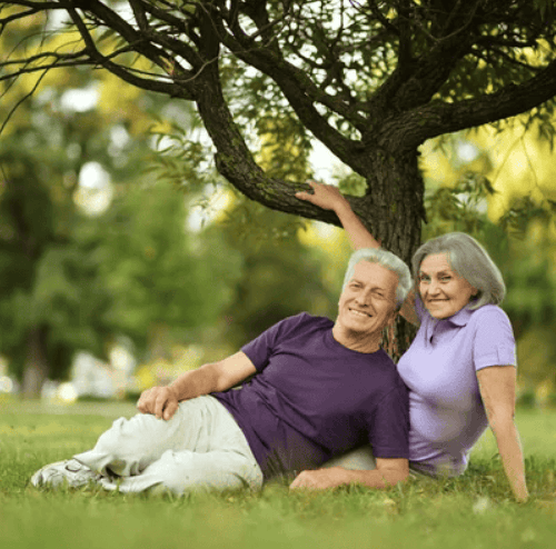 a old man and woman sitting on the grass