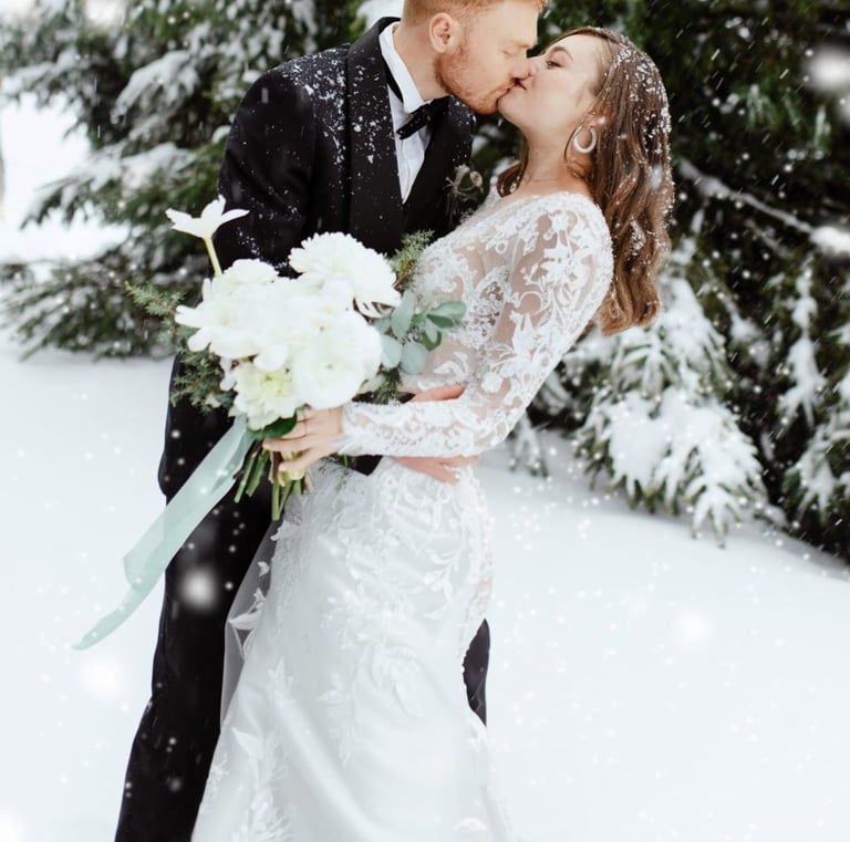 a bride and groom kissing in the snow