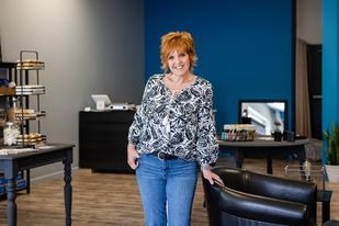 Laura standing in a room with a chair and a chair