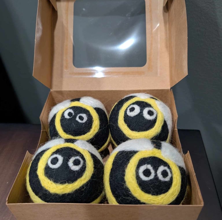a box of dryers balls with bees with eyes looking at you