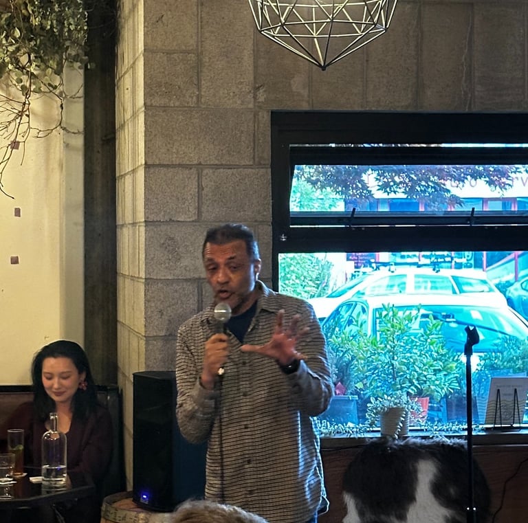 A man performing stand-up comedy with a microphone at an indoor live event venue.