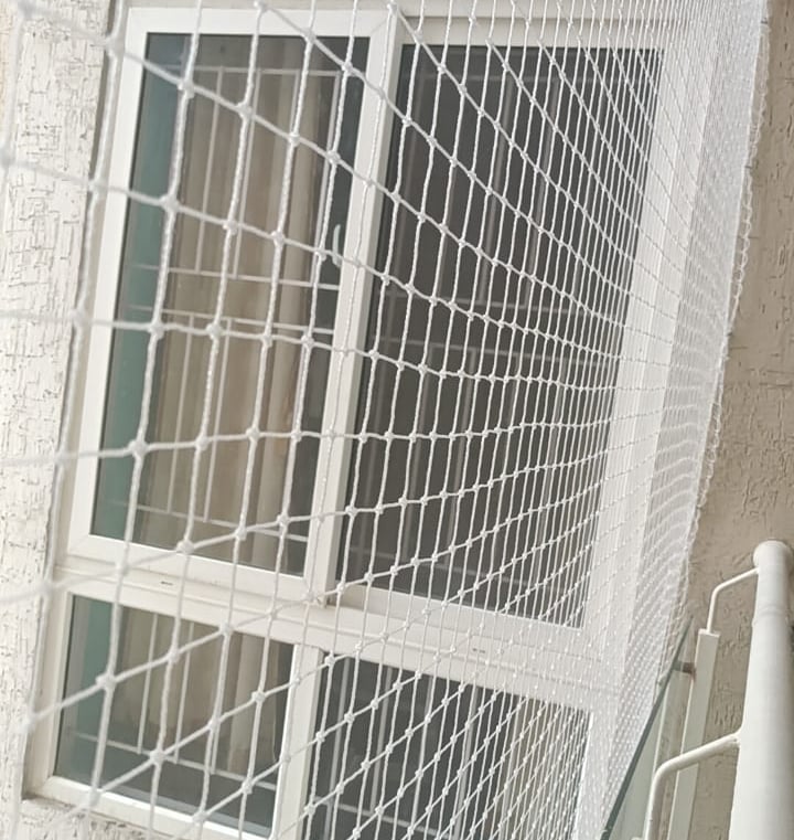 Technician carefully installing a safety net on an open area balcony.
