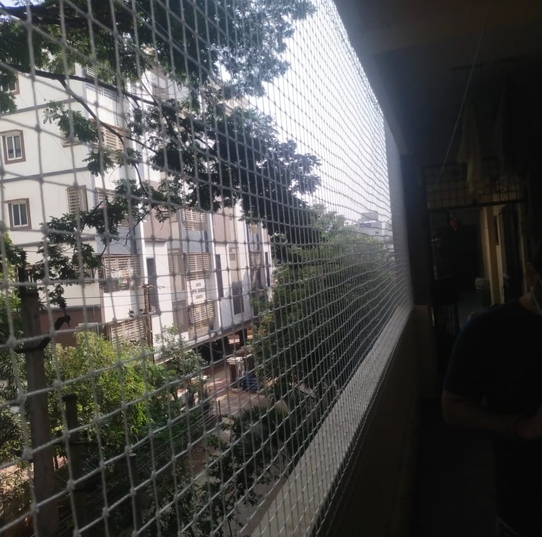 Hands of a technician from Arjilli Enterprises fixing an anti pigeon net on a railing.
