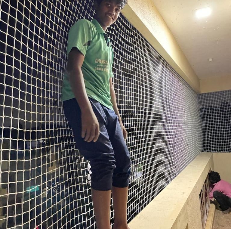 Child playing safely behind a balcony safety net installed by Arjilli Enterprises.