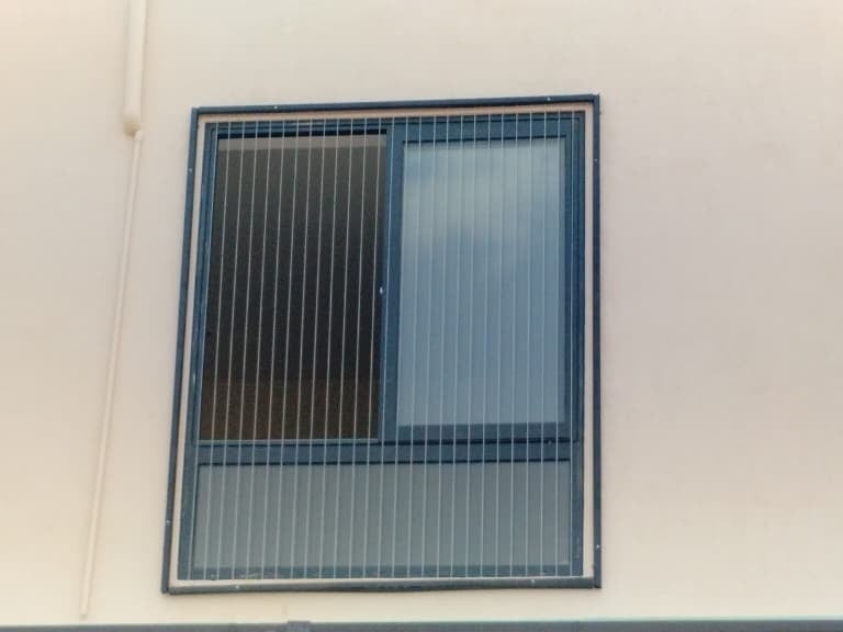 Close-up of a sleek invisible grill installed on a Besant Nagar balcony with a sea view