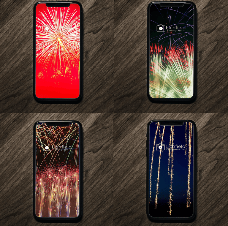 a group of four cell phones with fireworks in the background