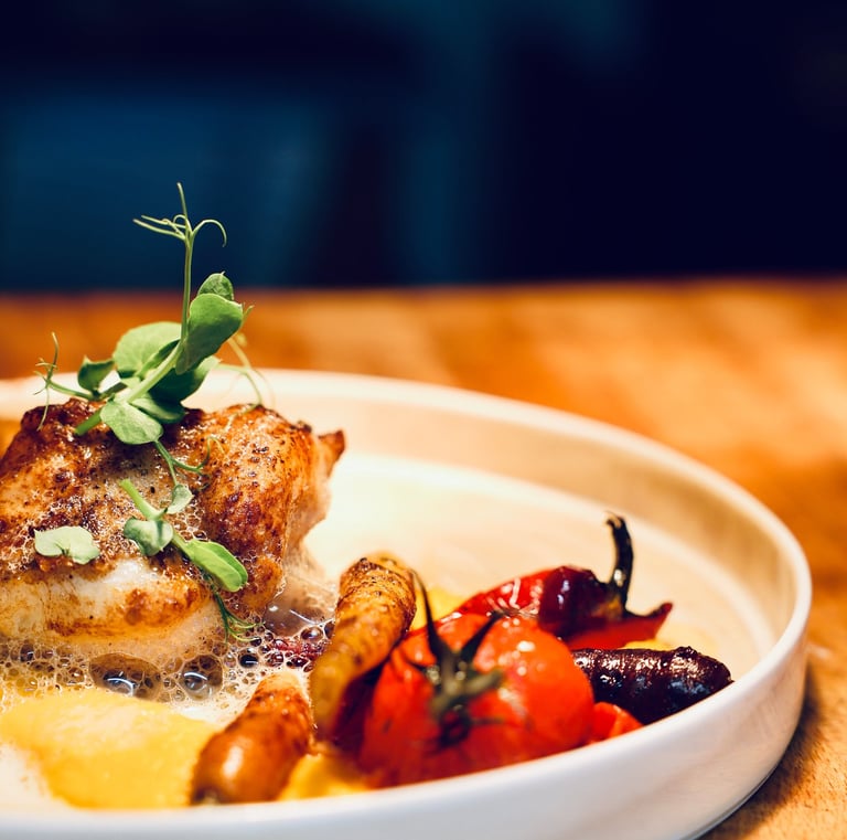 Gros plan d'une assiette blanche avec dedans un plat de poisson et des légumes entiers grillés