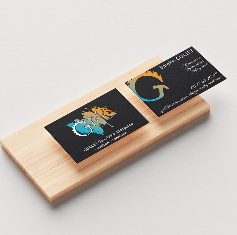 Cartes de visite de l'entreprise GMC posées sur un morceau de bois qui montre le recto et le verso