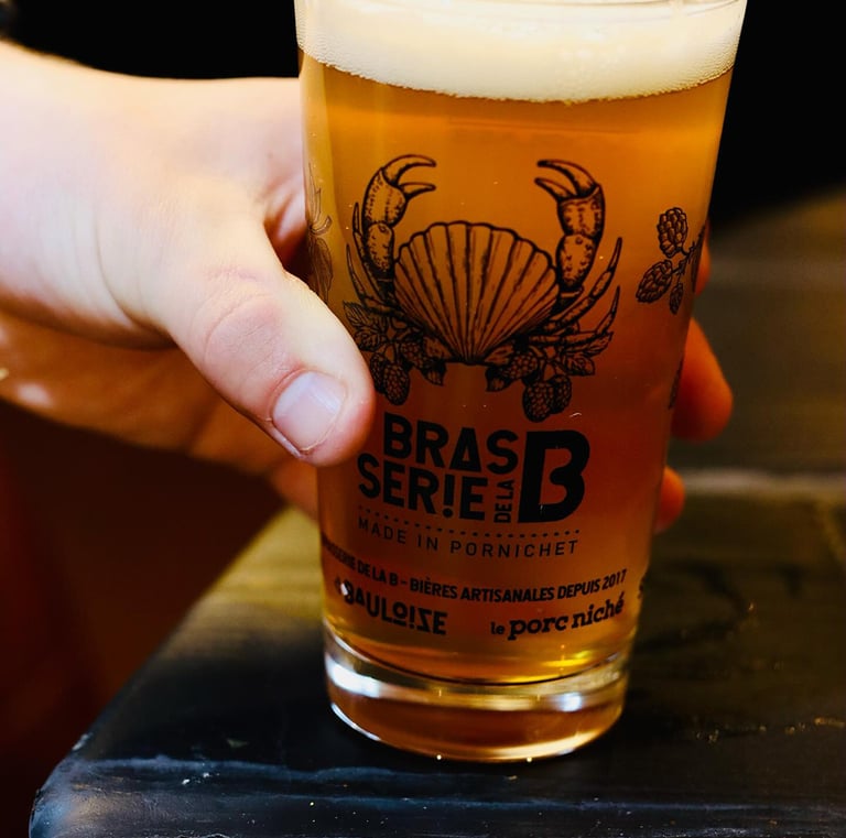 main en gros plan qui pose un verre de bière sur le bord d'une table en bois noir