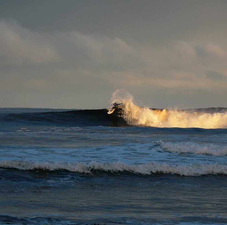 Surfing performing a snap with spray, early morning sunshine lighting uo the white water 