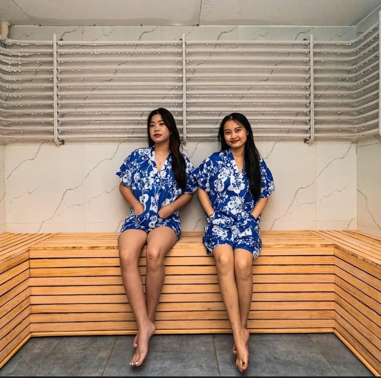 two women in matching blue pajamass sitting on a sauna bench