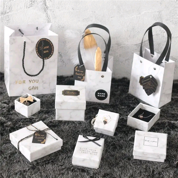 Elegant marble pattern gift boxes and shopping bags with black ribbons for luxury jewelry packaging.