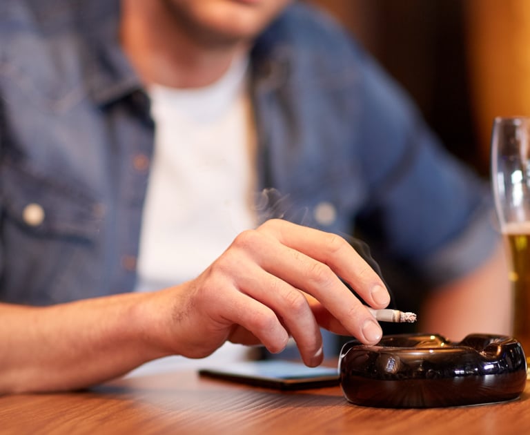 a man sitting at a table with a cigarette in his hand