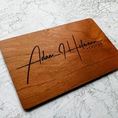 Wooden NFC digital business card with the name Adam J. Hofmann engraved.