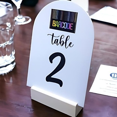 White acrylic table number 2 with a wooden base on a table.