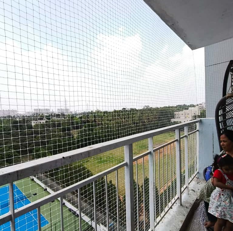 Wide shot of a colorful safety net protecting a play area in a Koramangala apartment.