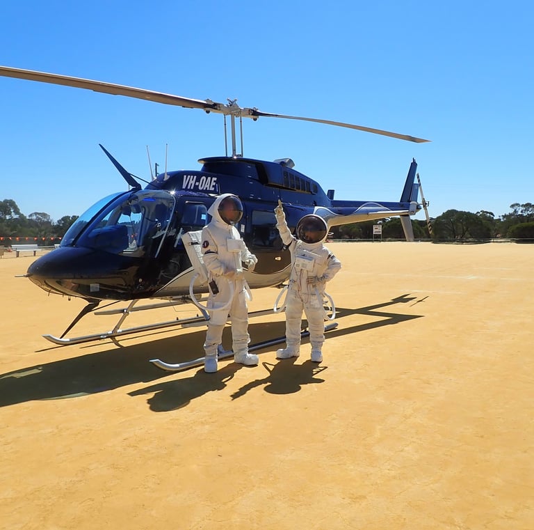 two astronauts standing in front of a helicopter