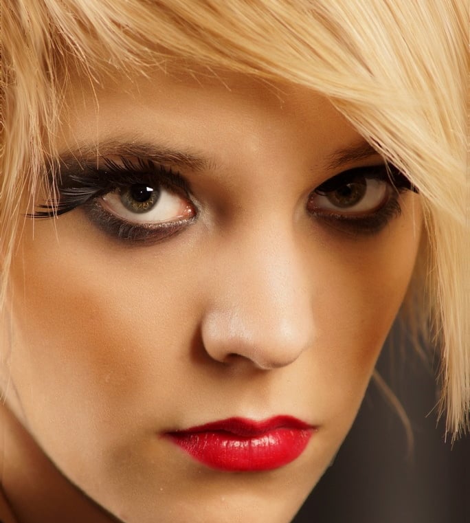 a beautiful woman with blonde hair, red lipstick and smokey eye makeup