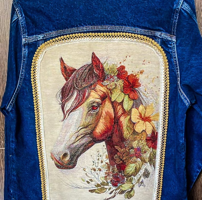Topacio-pintura textil y apliques de tela y randas sobre espalda de chaqueta de jean azul- Cabeza de caballo y flores
