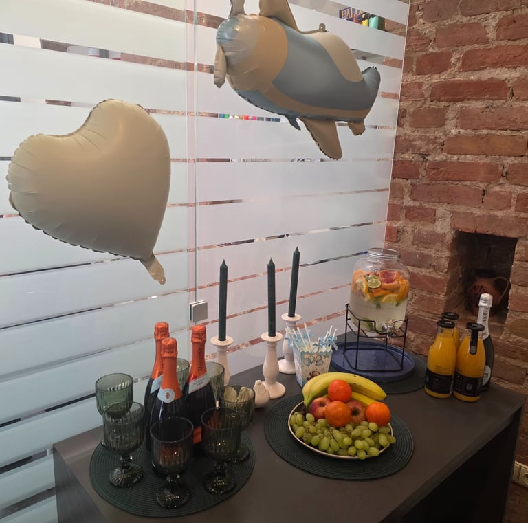 Party drinks and fruit platter with champagne and balloons on a table.