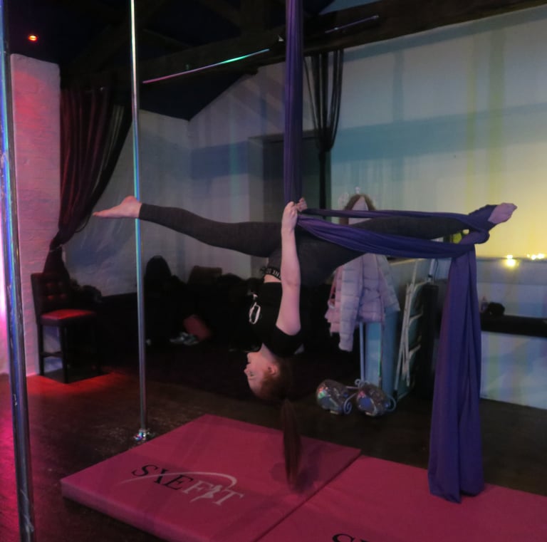 Image of student at Sxefit aerial silks class upside down in the splits