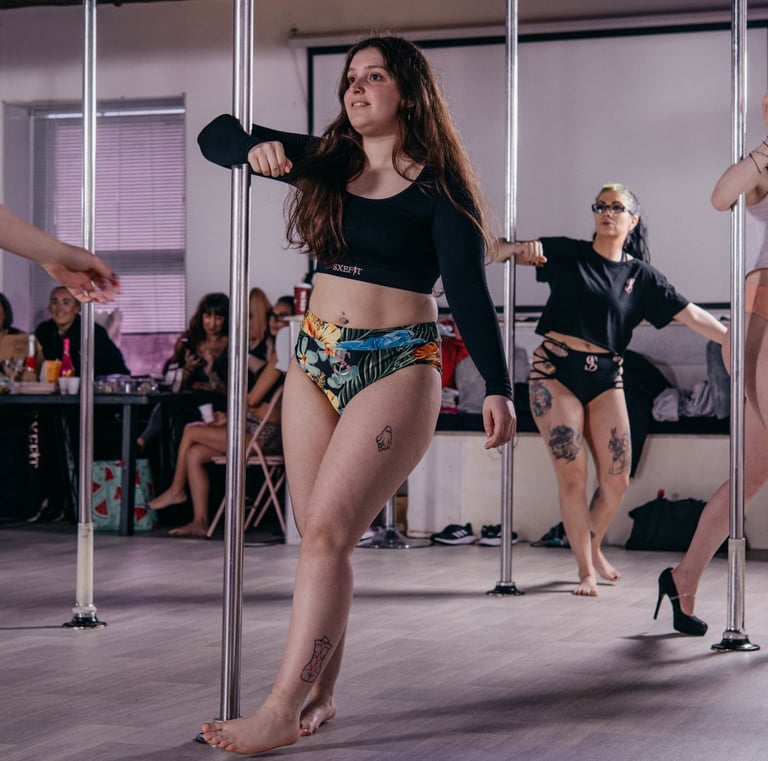 Image of student posing by the pole in a Sxefit pole dancing class