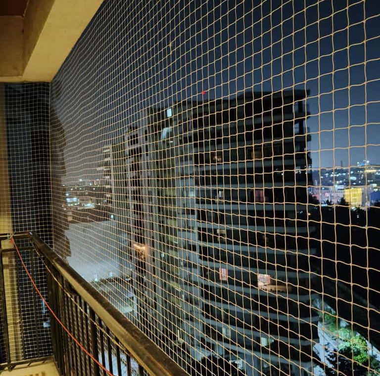 Evening view of a balcony with safety nets glowing softly under warm indoor lights