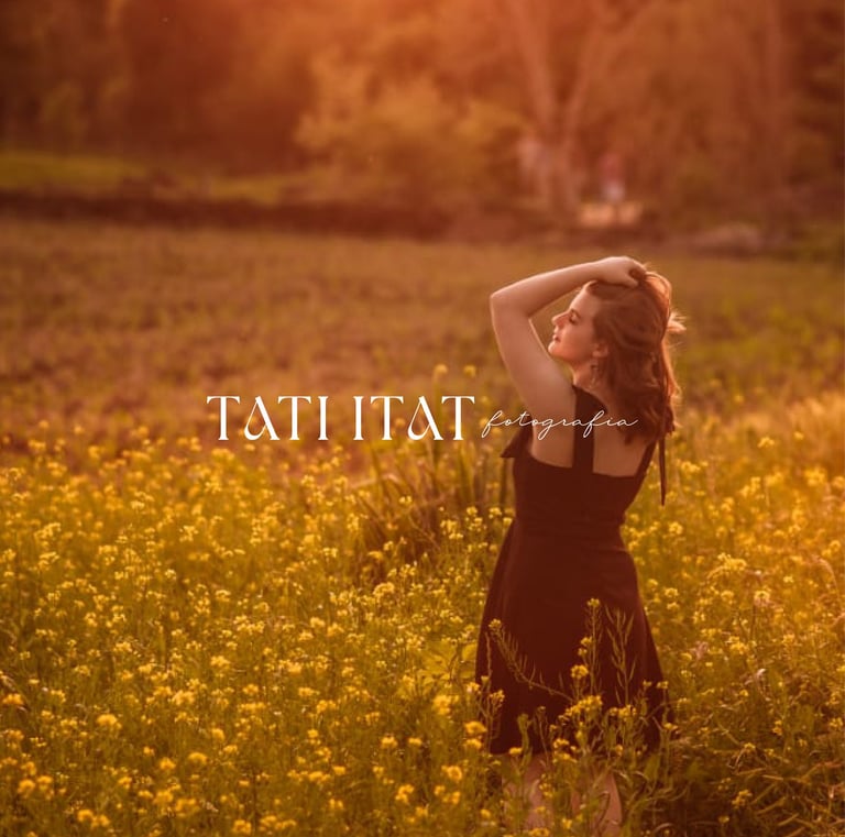 Mulher de vestido preto em campo de flores amarelas ao pôr do sol com o logo da Tati Itat Fotografia