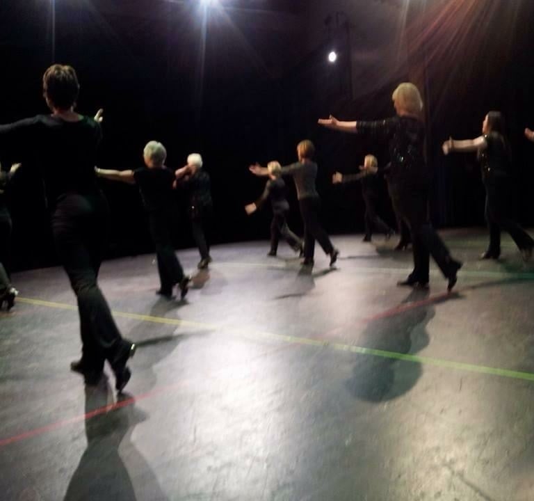 a group of adults tap dancing in a recital in a dance pose