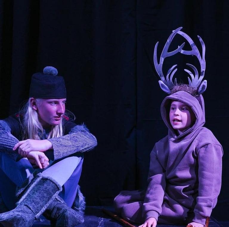 Two youth actors in costumes on stage performing Frozen Jr.