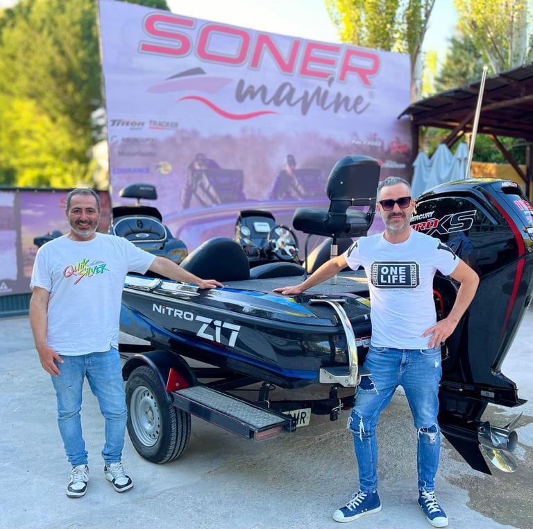 two men standing next to a boat with a motorbike