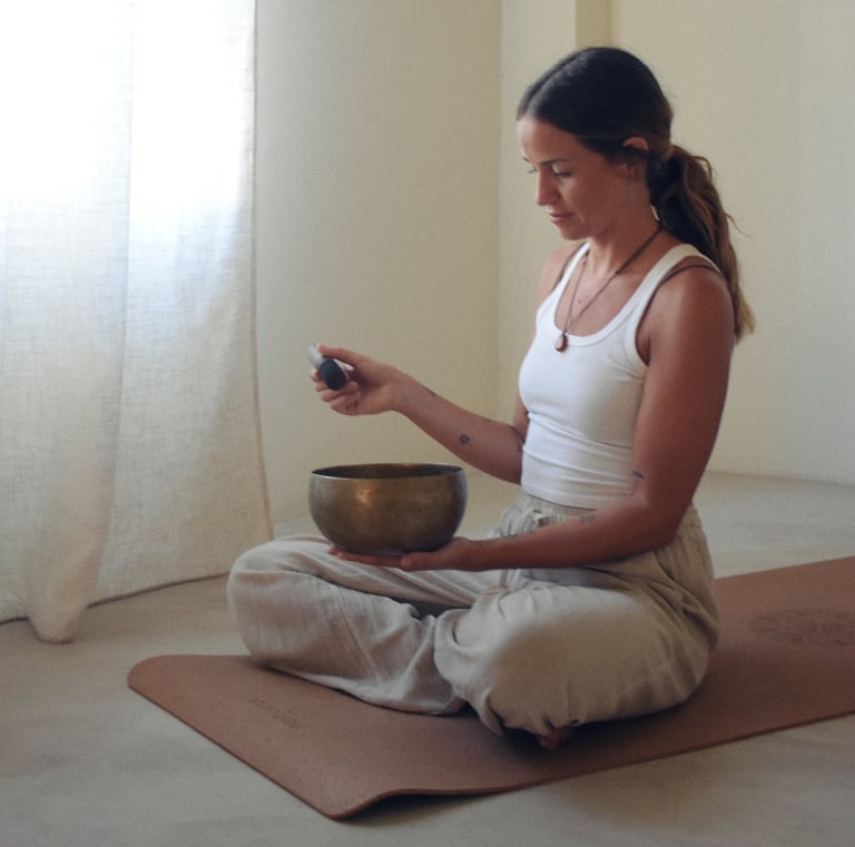 Chica sosteniendo un cuando tibetano, sentada con las piernas cruzadas. Vestida en tonos neutros.
