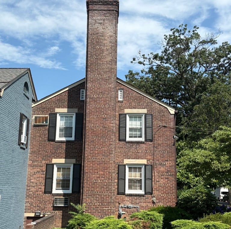 A tall, outdoor brick chimney on a house in Roslyn, New York, undergoing inspection for a major rebuild and repair project by