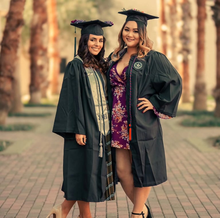 two women in graduation gowns posing for a photo